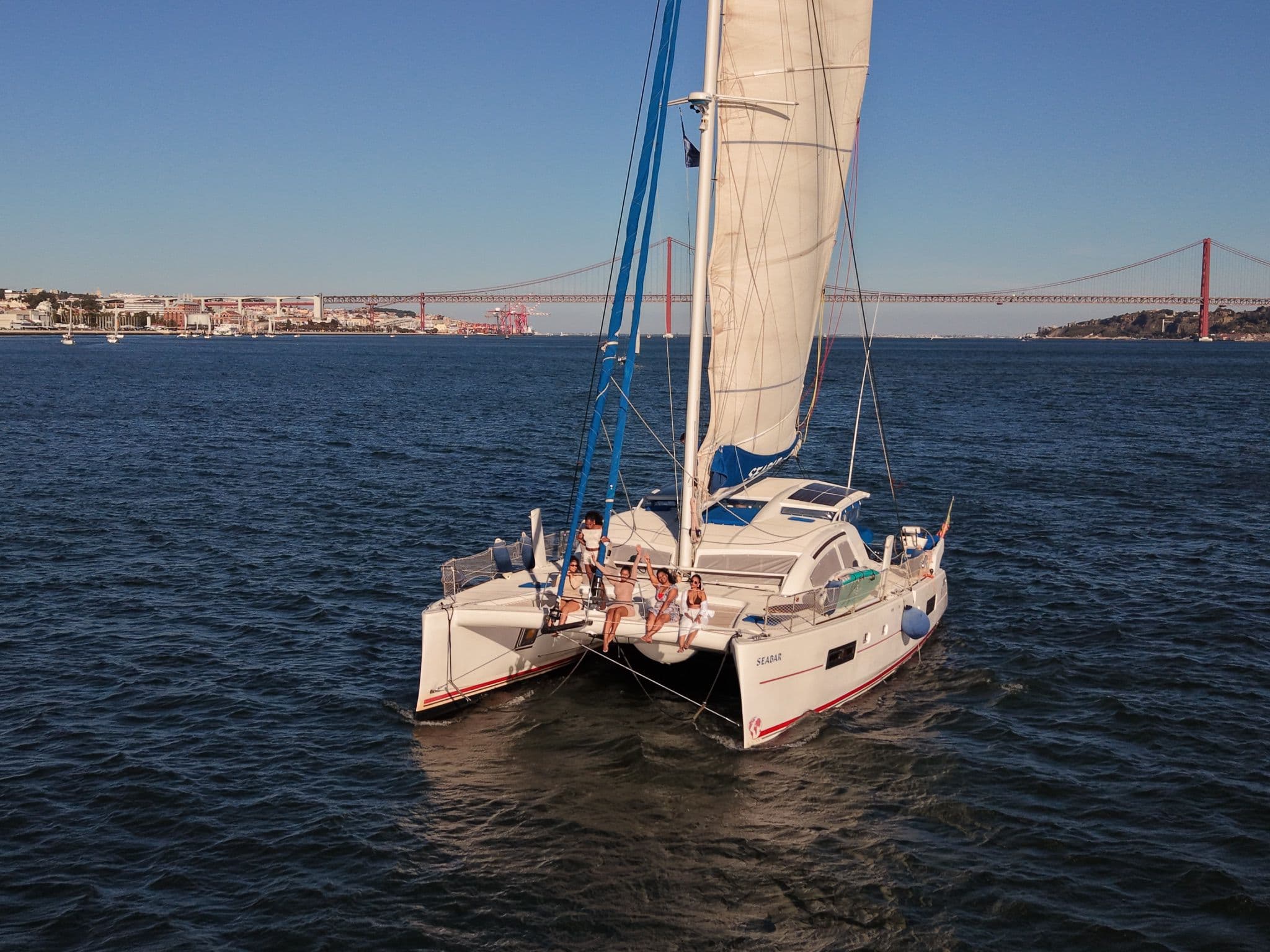 Passagers sur les filets du Seabar, avec le pont du 25 Avril en arrière-plan.
